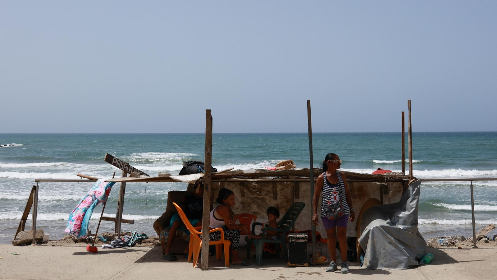 Dos mujeres y un niño se alojan en un refugio improvisado en una playa tras perder su hogar en el devastador terremoto de La Guaira