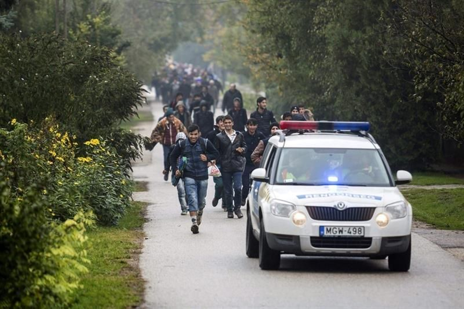 Varios refugiados caminan hacia Austria escoltados por la policía desde Hegyeshalom.