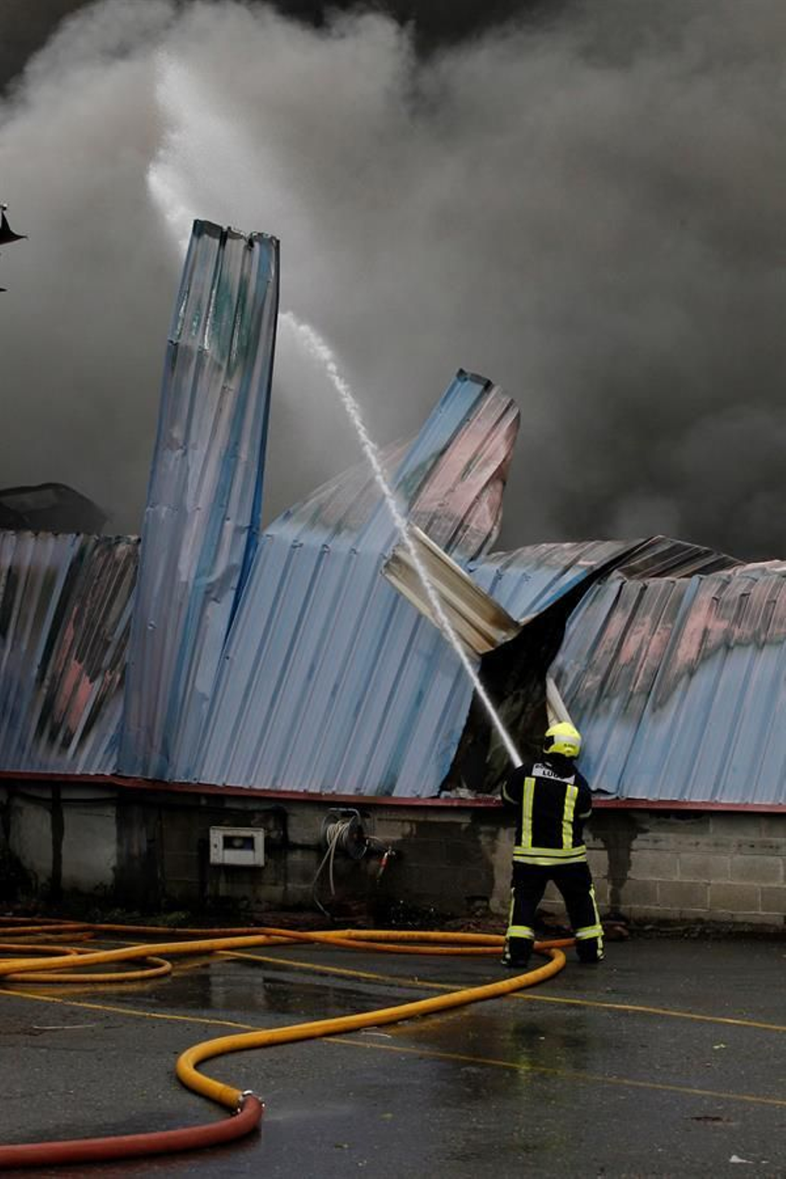 Varios bomberos intentan controlar las llamas de un incendio en el parque empresarial de O Ceao, este domingo. El secretario general del Confederación de Empresarios de Lugo (CEL), Jaime López, ha calificado este domingo como "un día negro para Lugo" por el incendio que ha calcinado al menos cuatro naves en el polígono industrial de O Ceao y que ha obligado a activar el nivel 1 del plan de emergencias de Galicia, aunque no ha provocado daños personales. EFE/Eliseo Trigo