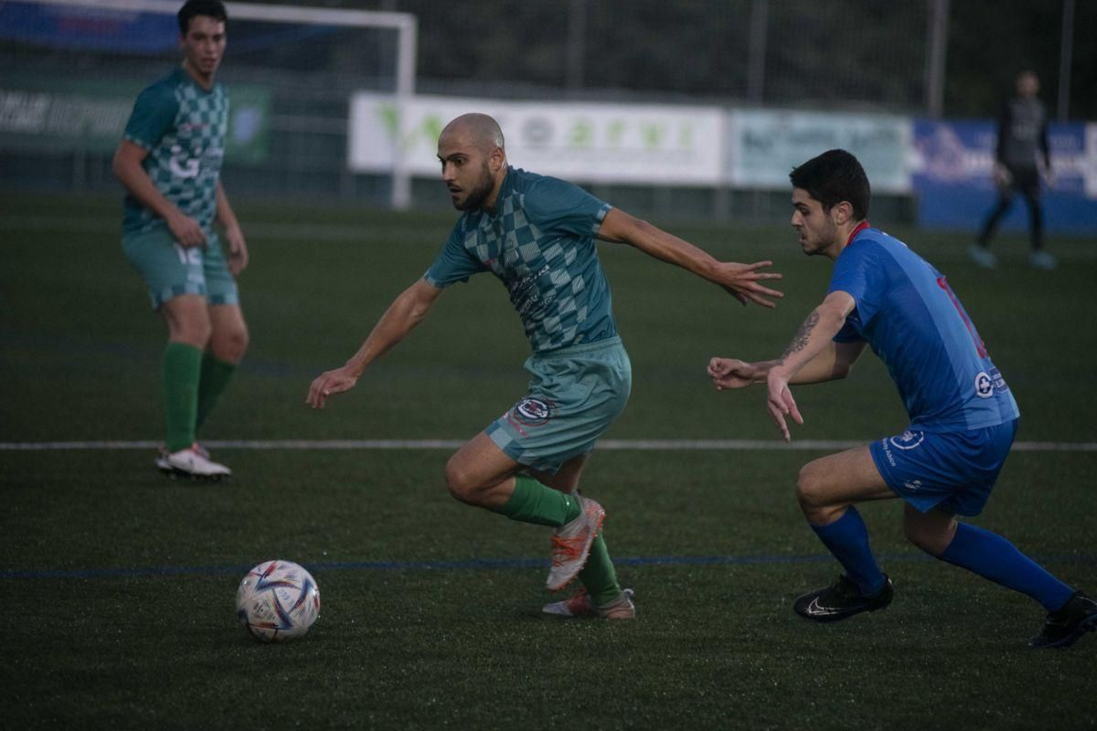 El medio Dani, del Melias, se marcha con el balón perseguido por el azulón Pablo Míguez (XF).