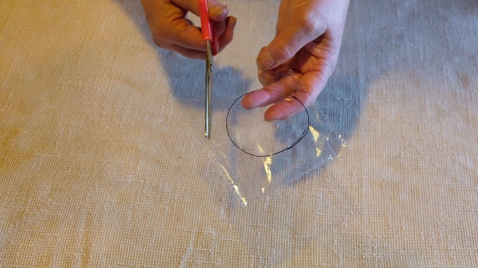 Colle agora os plásticos e, sobre eles, marca un círculo coa parte máis ancha do tubo de cartolina. Isto marcarache a área na que poderás debuxar para proxectar sobre unha parede. Para recortar, terás que deixar unha boa marxe para poder pegalo contra a cartolina sen problema.