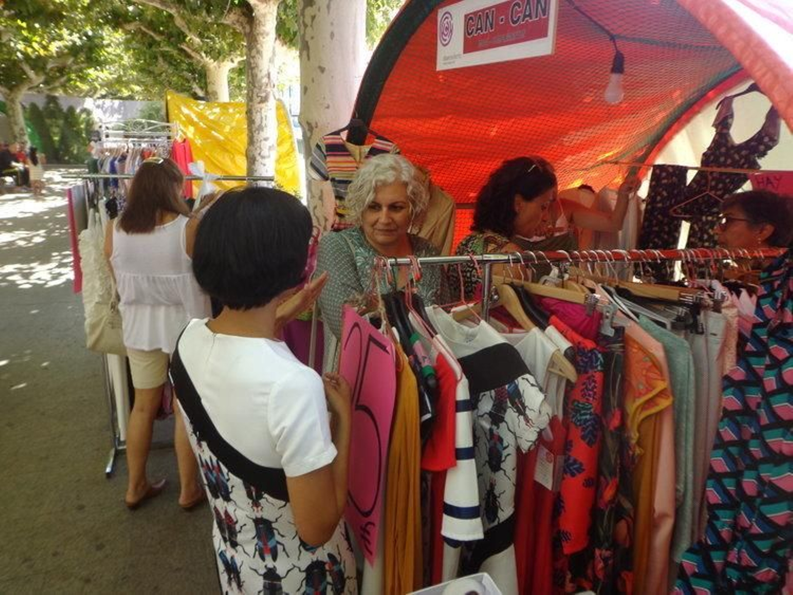 Clientes en un puesto de prendas de vestir.