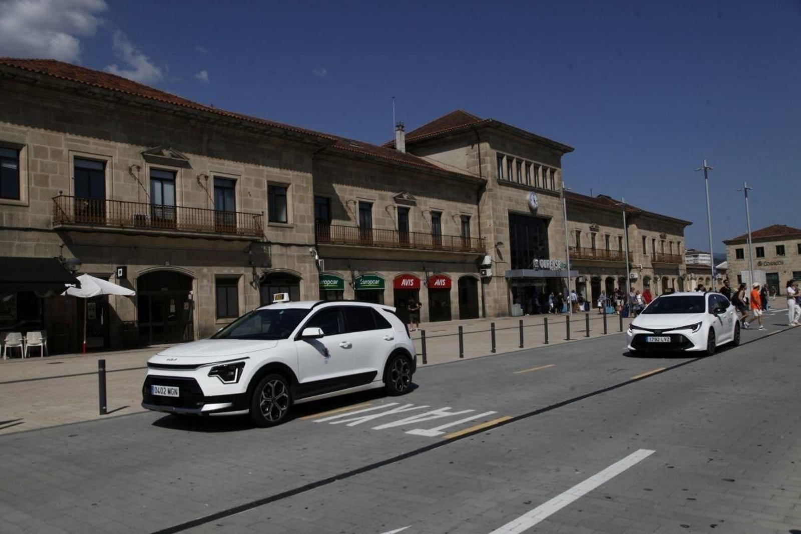Taxistas esperan al sol en la estación de tren.