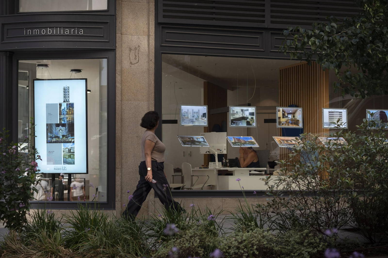 Una ourensana pasa por delante de una inmobiliaria en la ciudad.