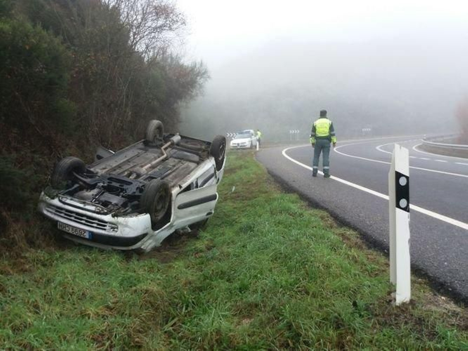 El coche volcado. En la calzada, un agente de Tráfico vigila la circulación en la N-525.