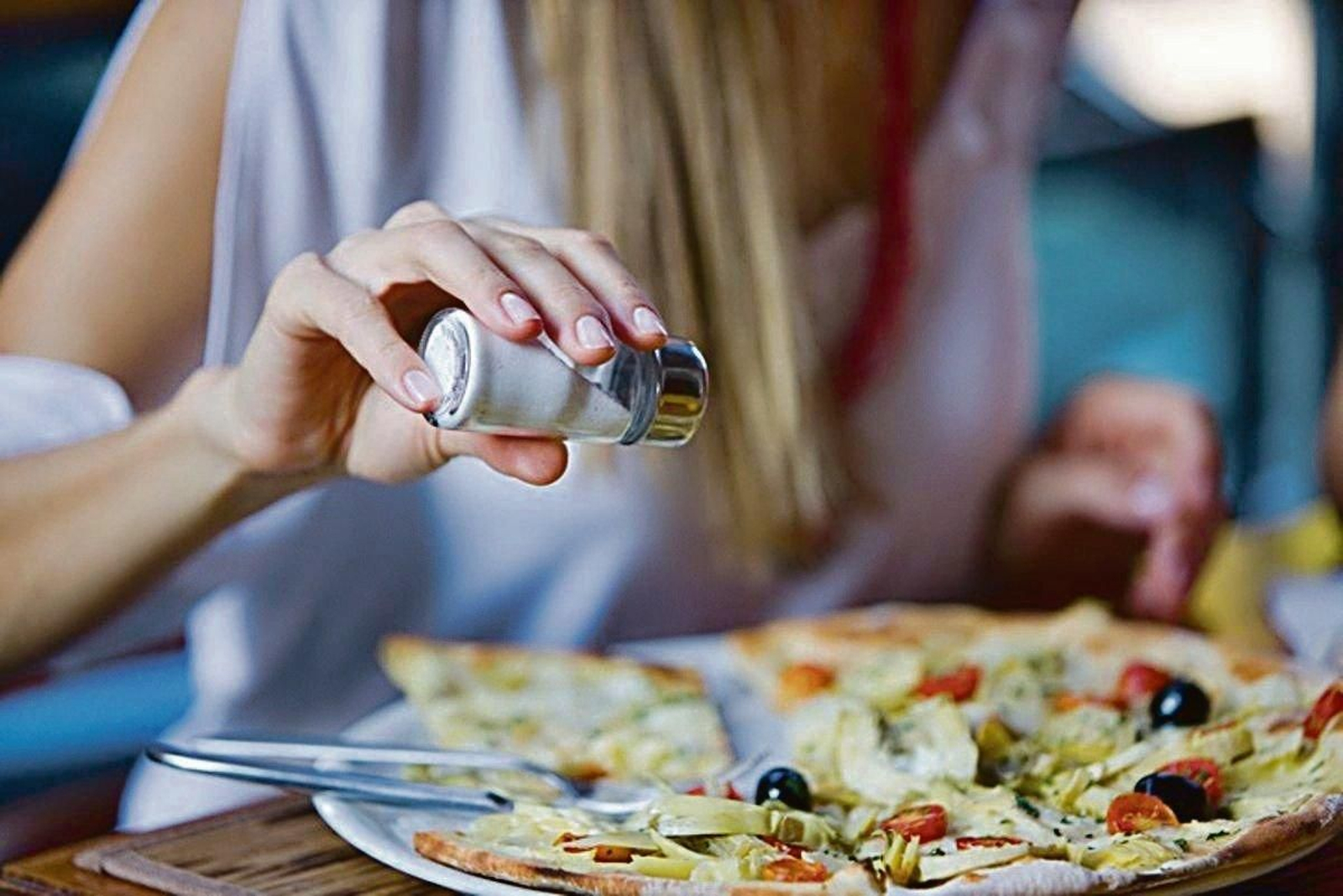 Una mujer añade abundante sal a un plato.