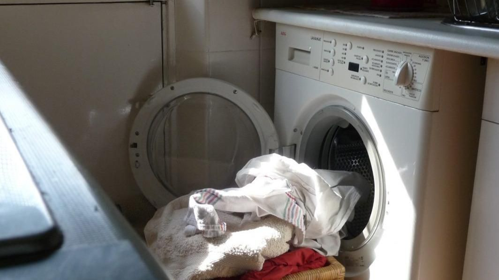 Cesta de ropa preparada para ser introducida en la lavadora de una vivienda.