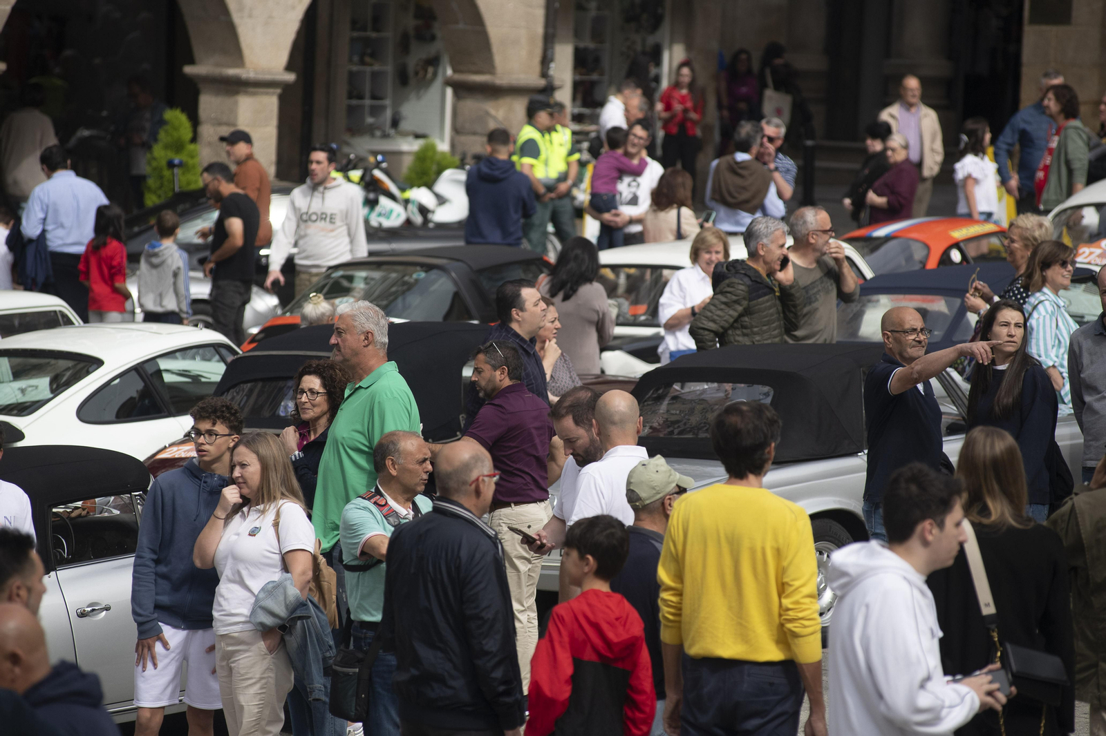 Gente observando los coches de rally antiguo expuestos en la plaza mayor de Ourense