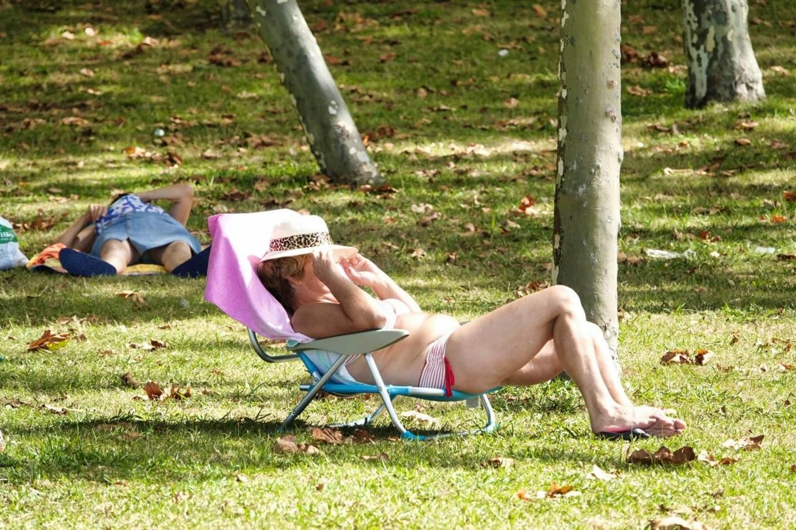 Una persona sentada en una silla de playa se tapa del sol. // Vicente Alonso