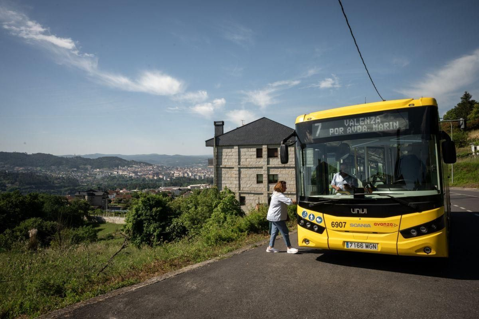 Una mujer sube al bus en la primera parada de la línea 7 en Cudeiro