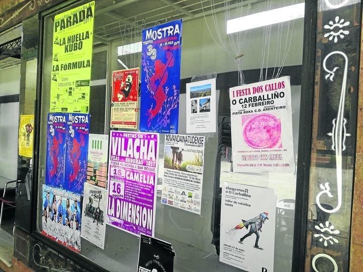 Escaparate de un bajo comercial en la Rúa do Paseo, lleno de cartelería.
