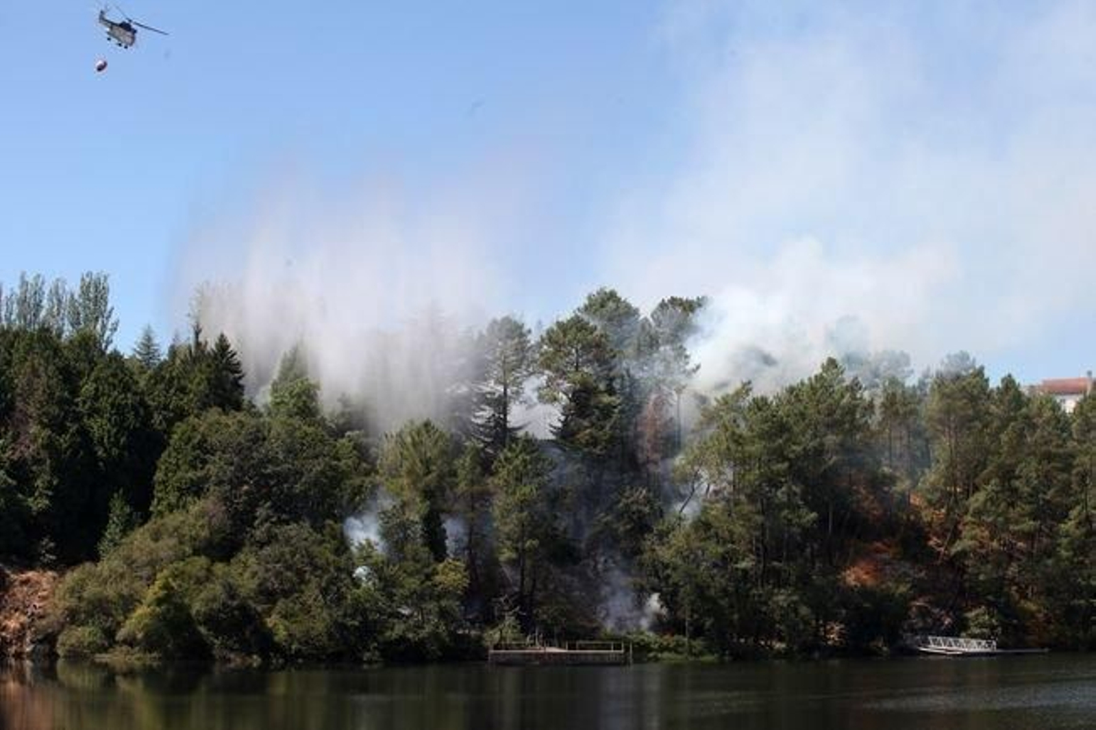 Un helicóptero arroja agua sobre el fuego declarado en la presa de Velle.
