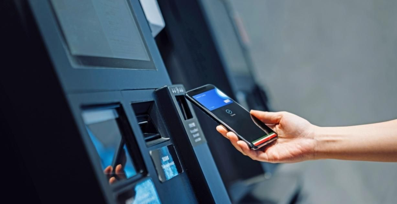 Una persona utiliza su teléfono móvil en un cajero