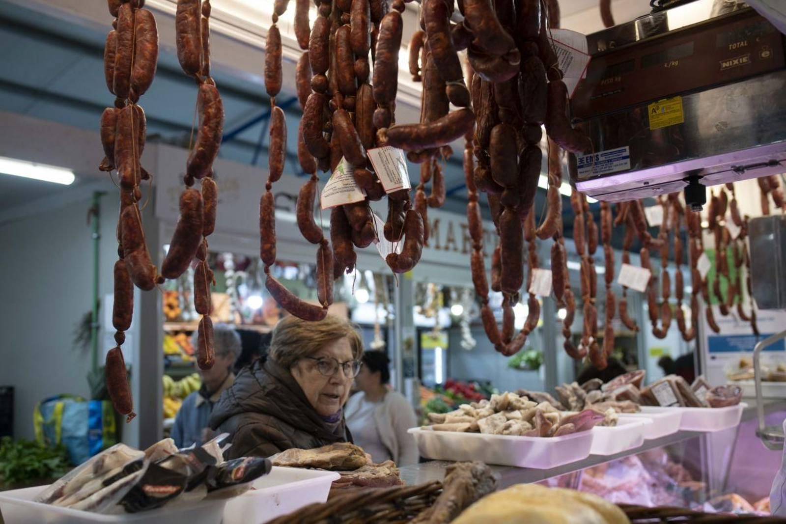 Una mujer observa el género en una carnicería de la Praza de Abastos número 1.