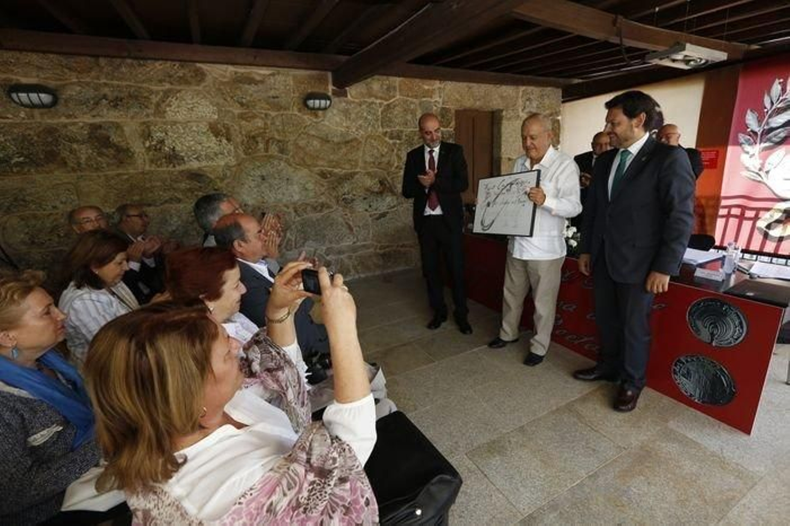 Roberto Ogando, entre Ferro y Miranda, co galardón, recibindo os aplausos dos asistentes.