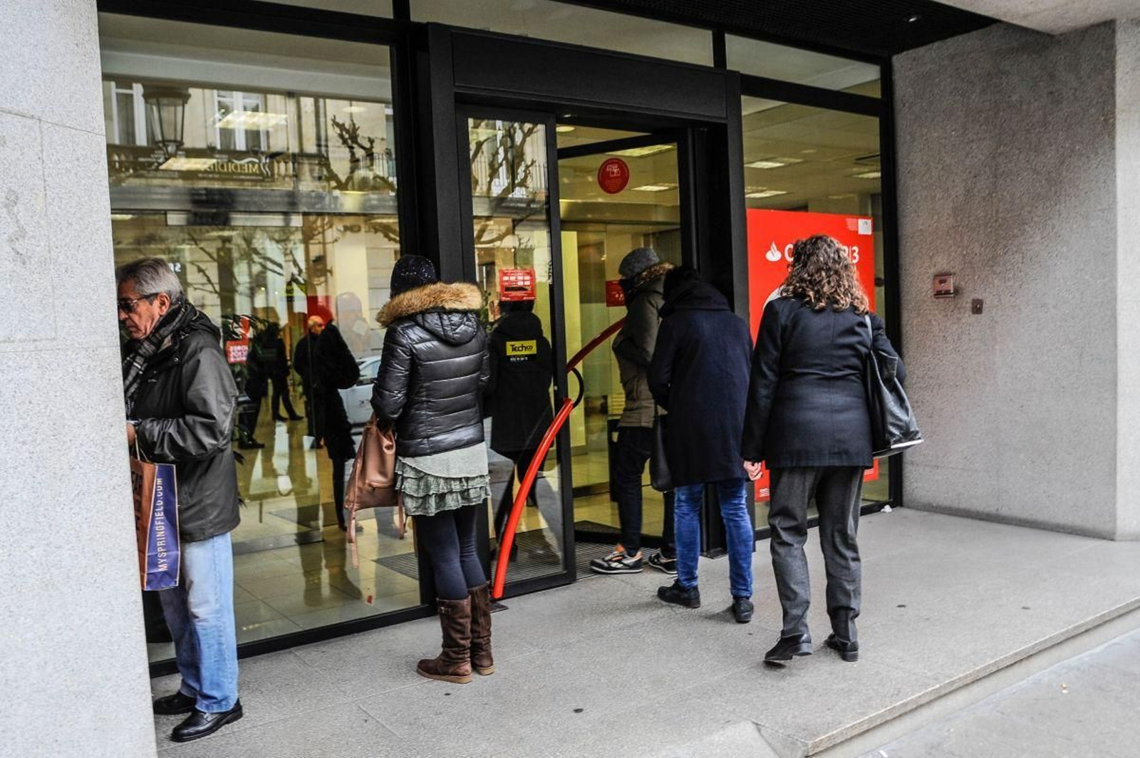Clientes a la entrada de una oficina bancaria de la ciudad en una imagen de archivo.