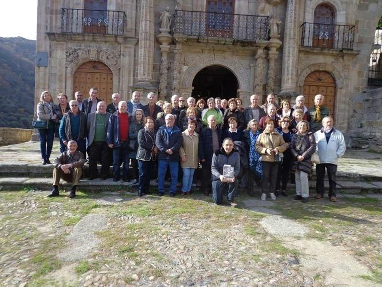 El presidente de los cofrades posa, agachado, ante un grupo de pensionistas que visitaron el santuario.
