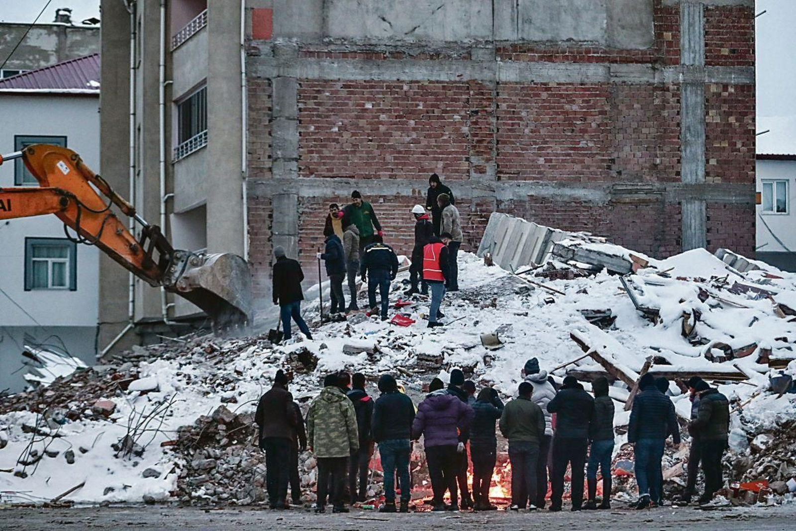 Varias personas buscan a personas entre los escombros.