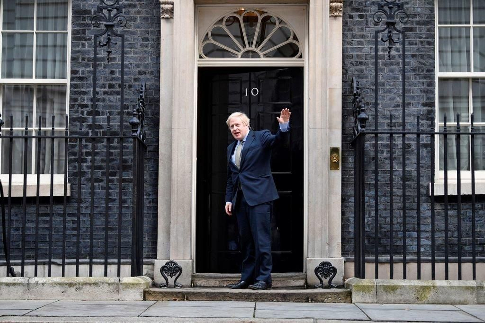 Boris Johnson saluda a los medios desde la puerta de su residencia oficial en Londres.