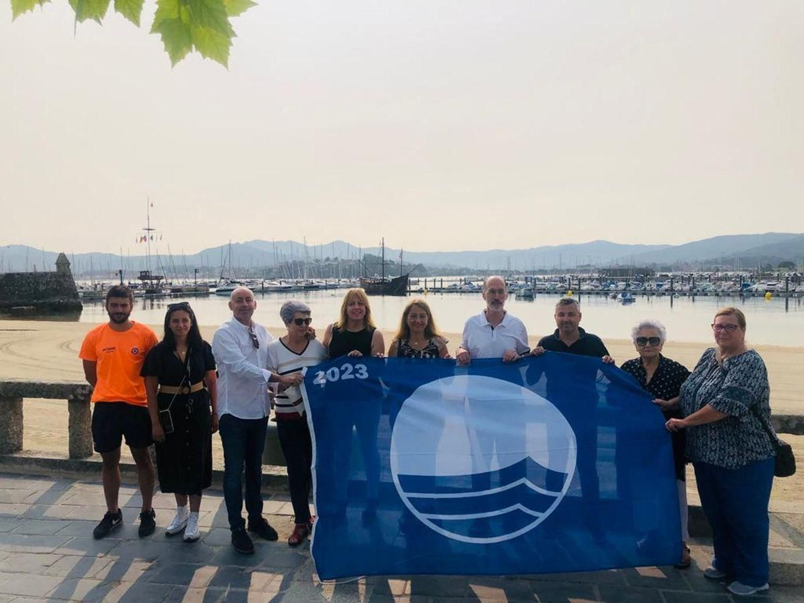 El alcalde Almuiña, con algunos de sus concejales, en la playa de Ribeira, con bandera azul.