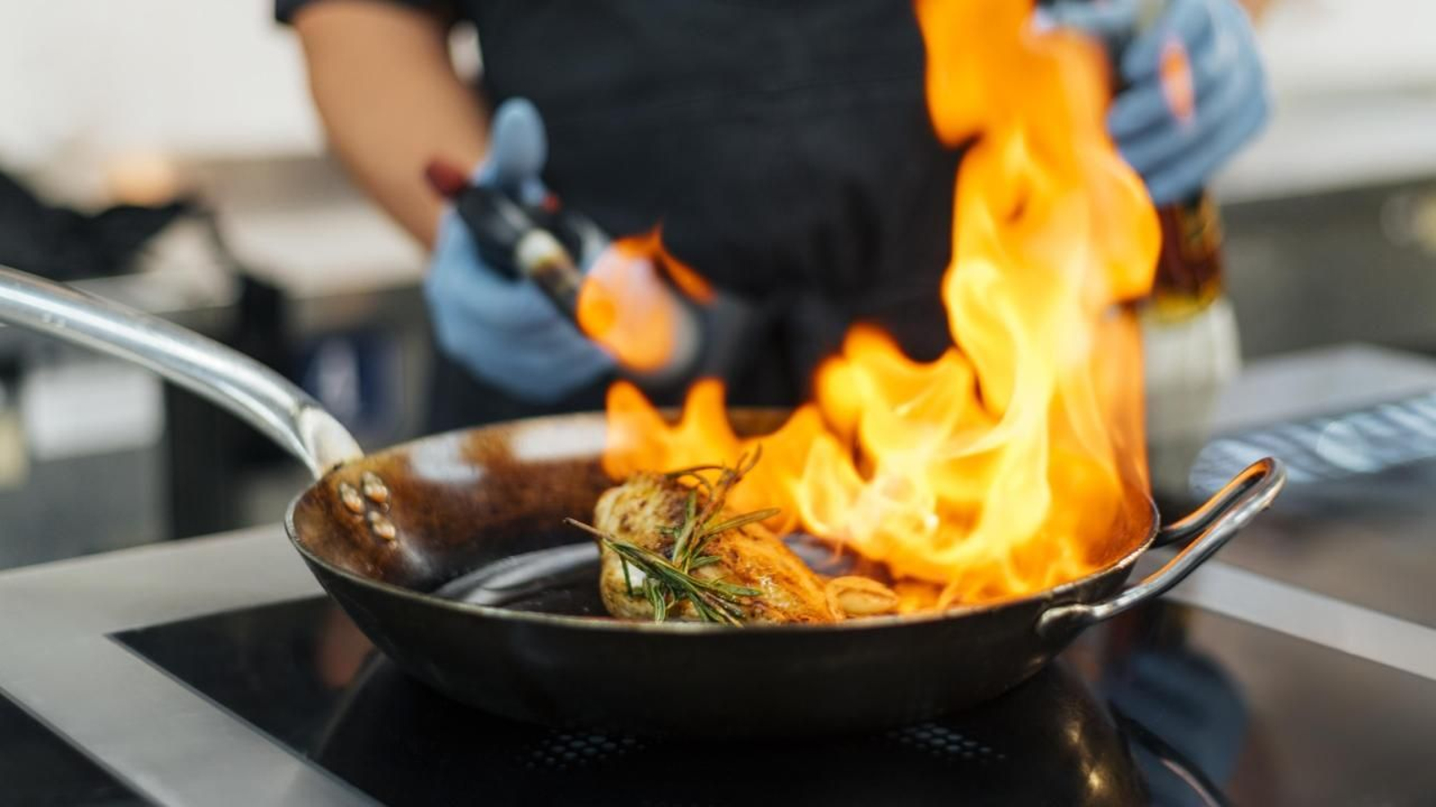 Un chef flamea un plato mientras cocina. FP