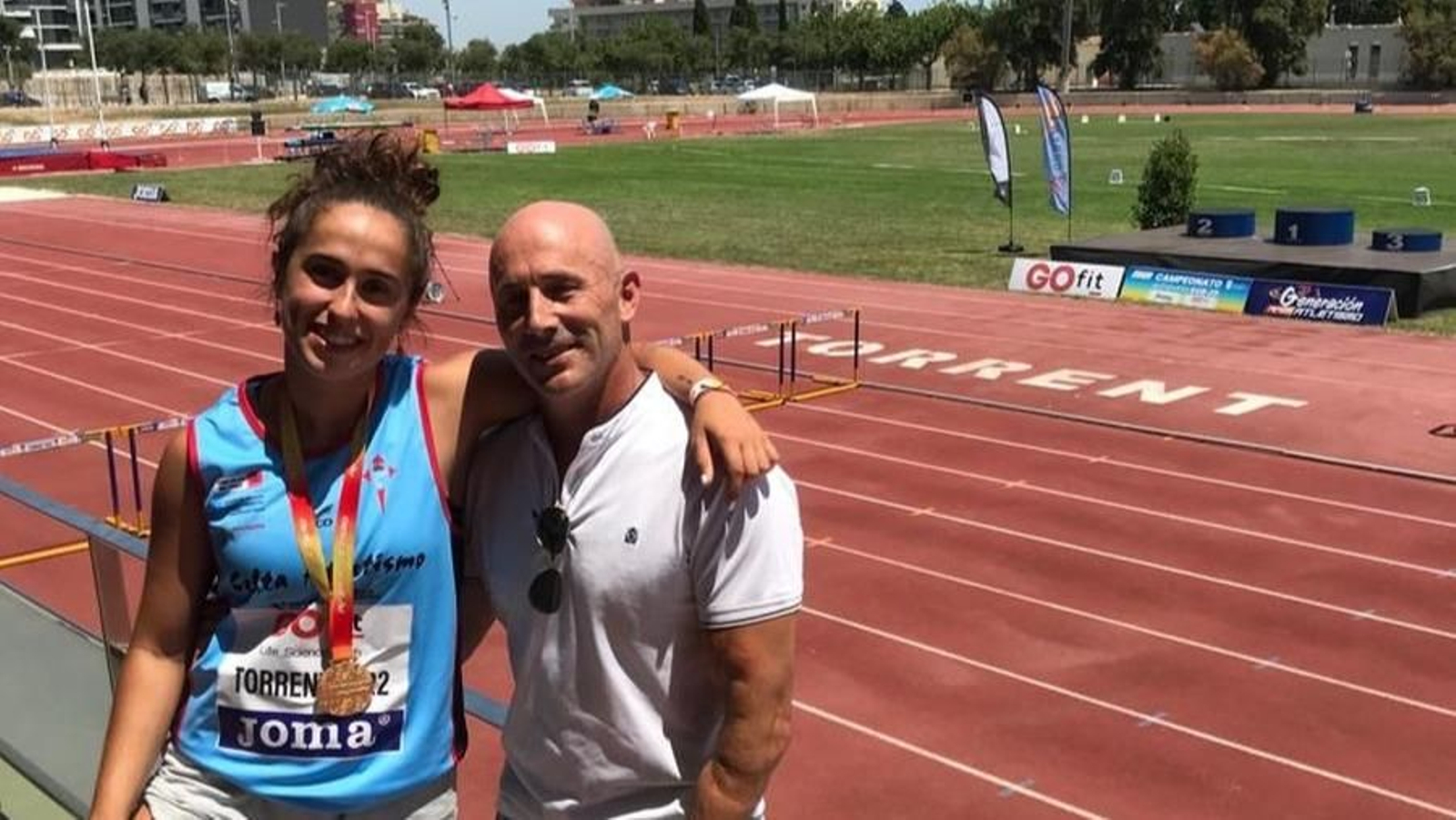 La joven lanzadora del Celta posa con su medalla de oro y su técnico.