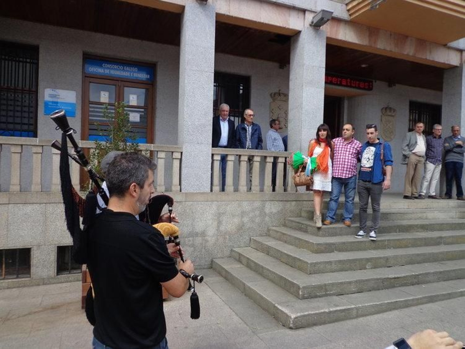 María González, Avelino Fernández y Germán Alejandre, ante los dos gaiteiros que tocaron el himno gallego.