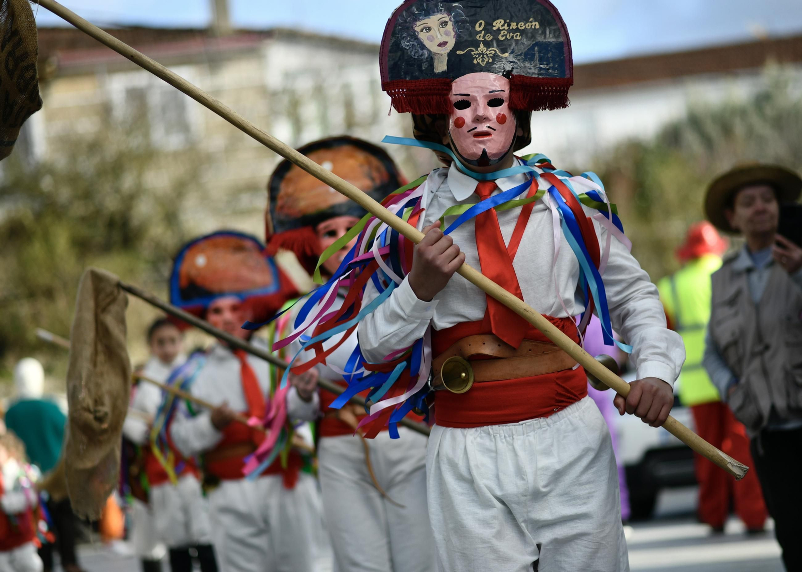 Los chocalleiros recorren las calles de Vilardevós con sus caretas y varas de harapo durante el día grande del Entroido.