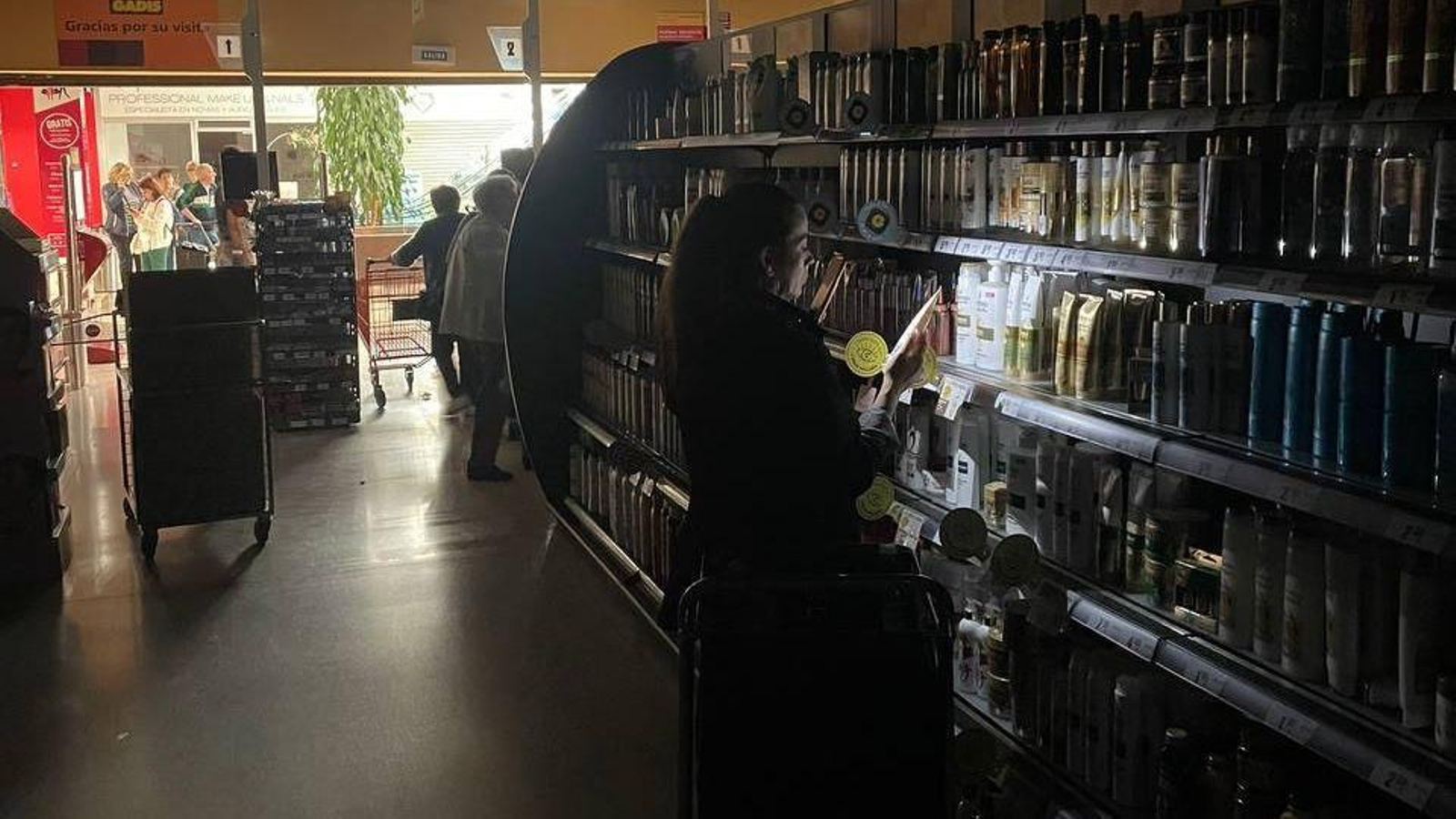 Una mujer comprando en un supermercado de Vigo, con la linterna del móvil.