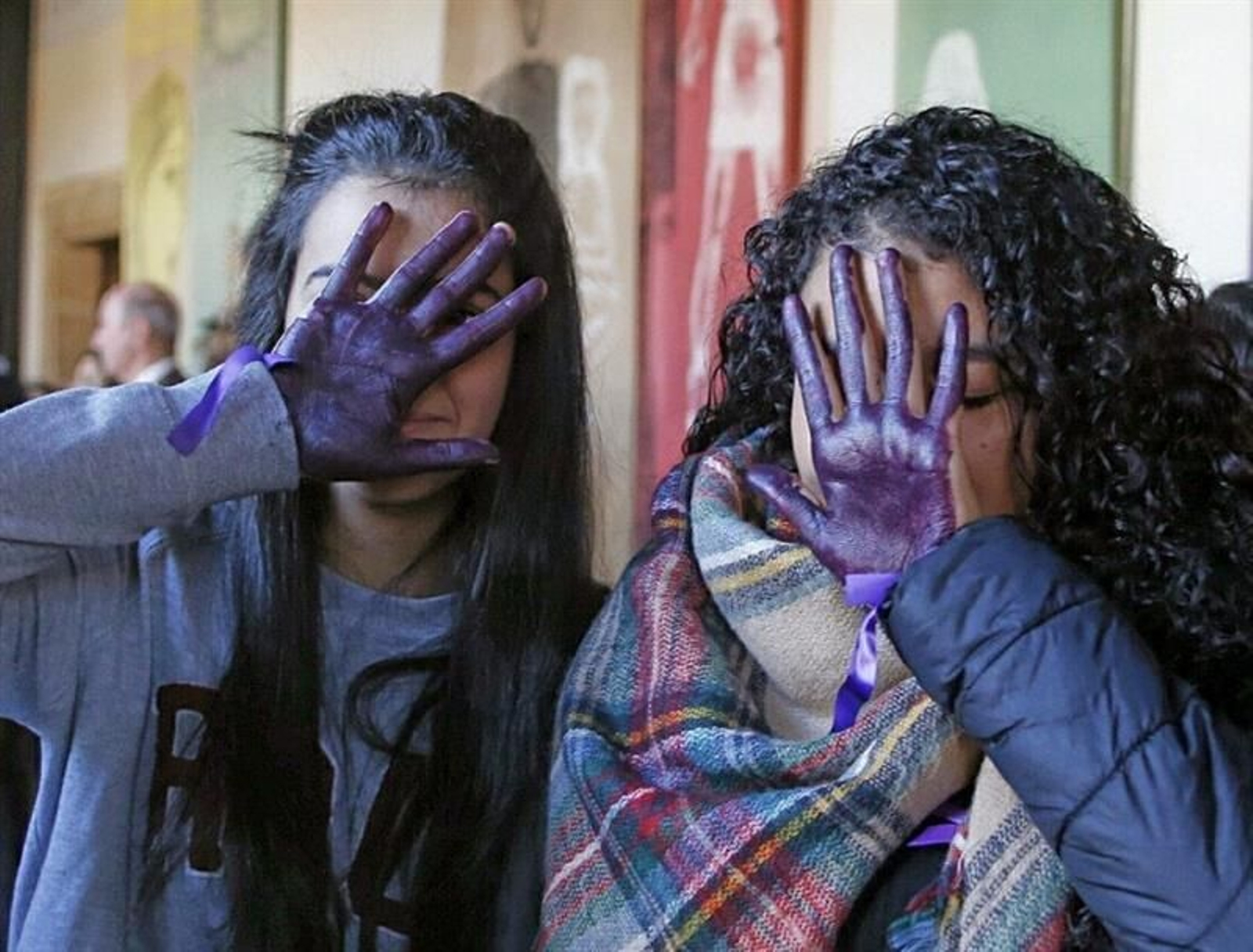 Dos alumnas de un instituto de Santiago de Compostela se tapan la cara con sus manos pintadas de violeta para manifestar su repulsa contra la vilolencia de género. (XOÁN REY)