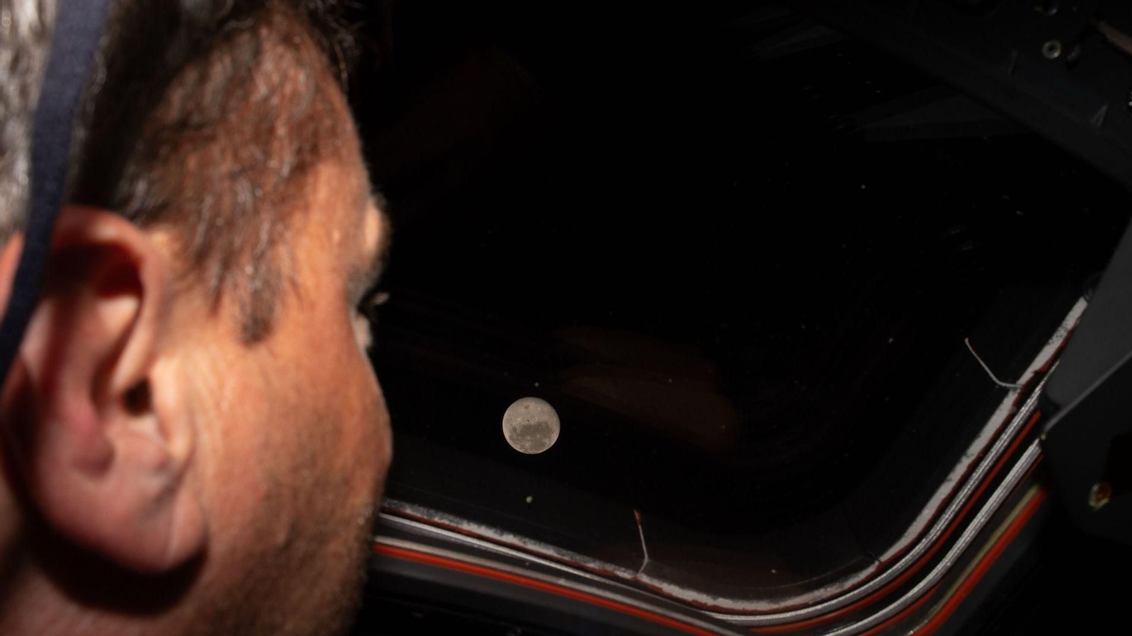 Reid Wiseman mira la luna por la ventana.