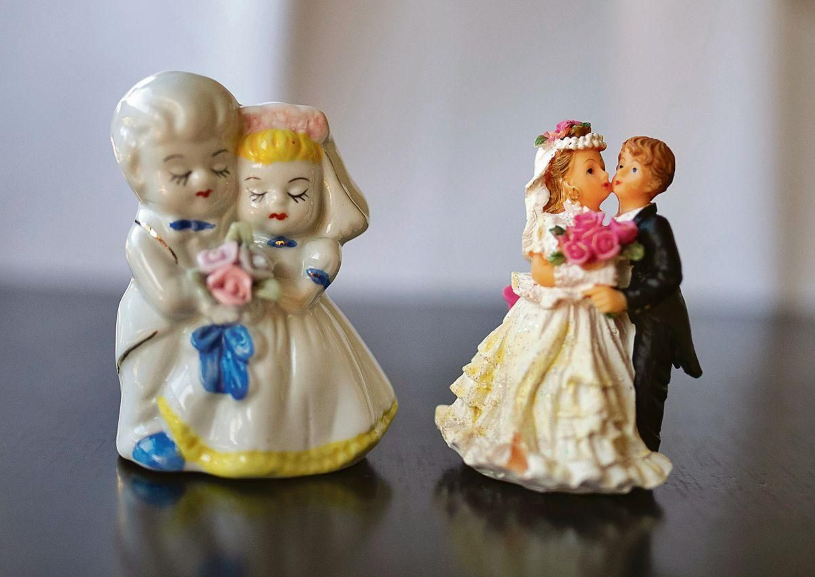 Dos pequeñas parejas de novios en cerámica, compradas por un euro en la Feria del 17, portando potentes ramos de flores.