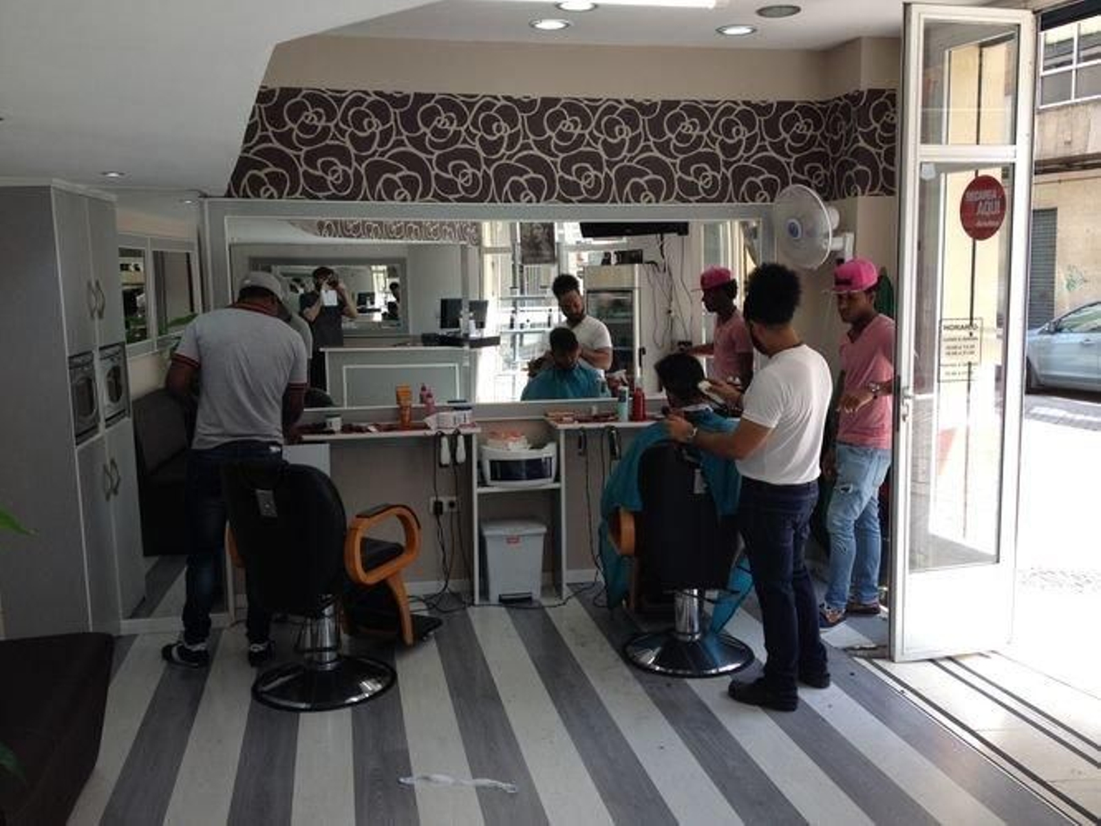 Panorámica de la peluquería Rachel, con los dos responsables, 'El Mayor' (izquierda, de espaldas) y Osvaldo Zabalea, pasando la maquinilla a Cristian.