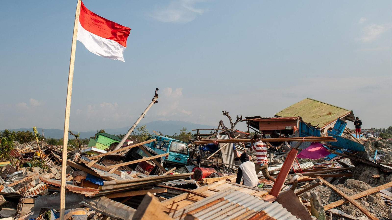 Se puede ver a los residentes caminando sobre las ruinas de un edificio que fue destruido por el terremoto de Indonesia.