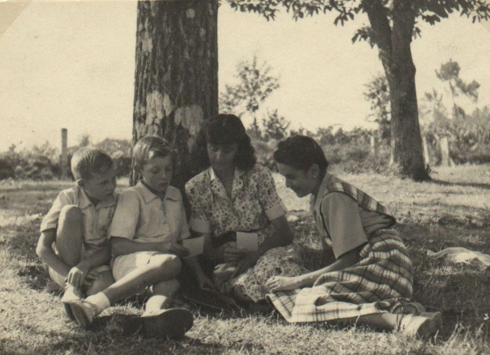 No álbum num. 3 de Carmiña aparece en esta foto de 1938 na que examina outras fotos no Campo de Roma, en Piñor, coa súa irmá e outros nenos.