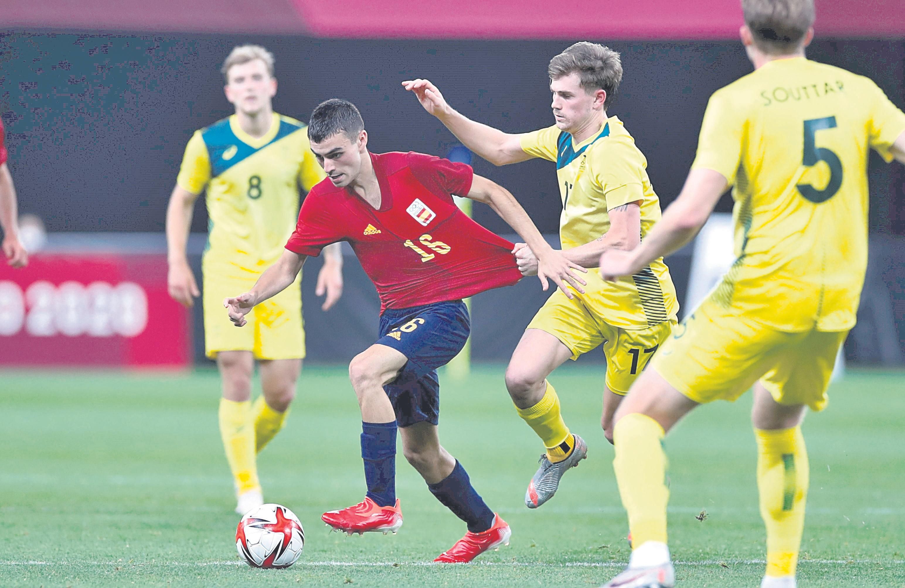 Pedri, medio de la selección española, intenta zafarse del agarrón de Metcalfe, de Australia.