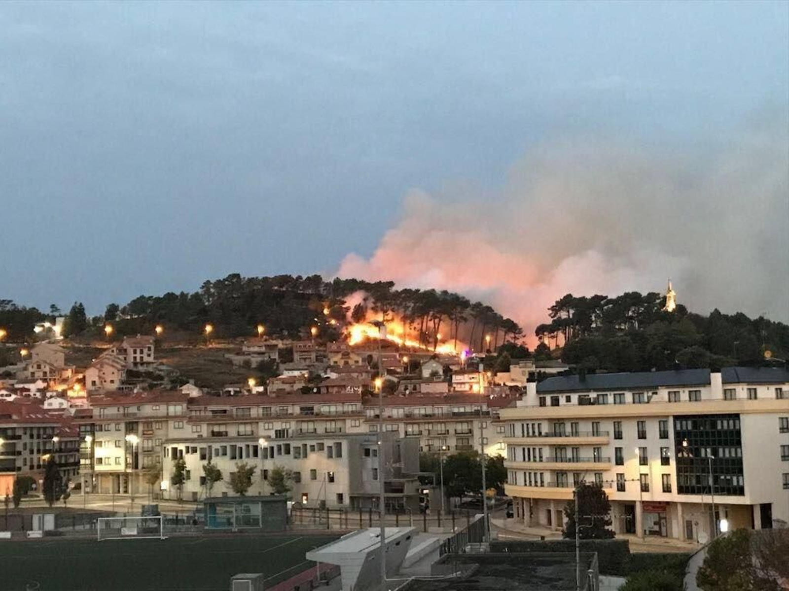 Arriba, el aspecto del incendio de Baiona a primera hora de la tarde, donde ya amenazaba las viviendas.