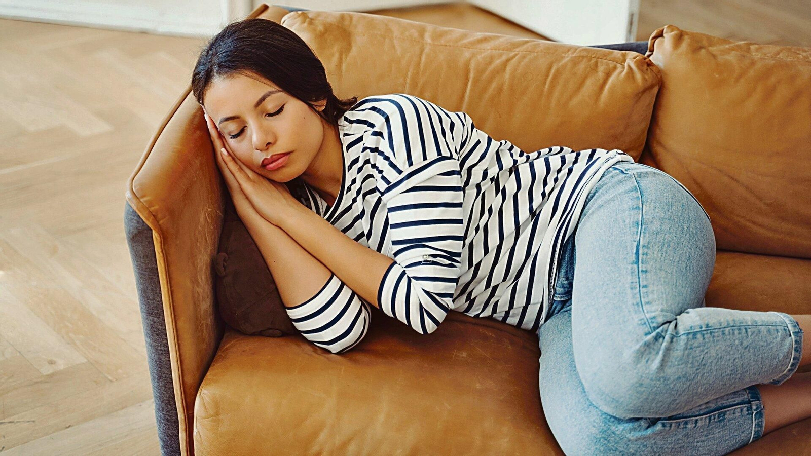 Una mujer echa una siesta en su sofá.