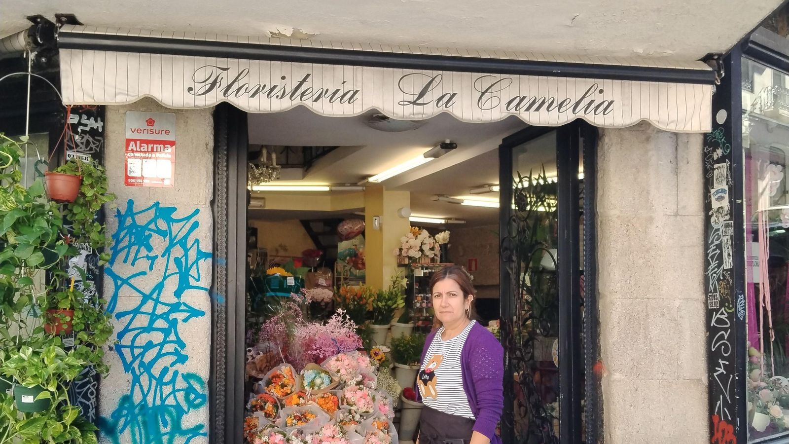 Elvira Rosario muestra las pintadas en su floristería, que afectan tanto al escaparate como a la pared de piedra e incluso a lo alto de la puerta.