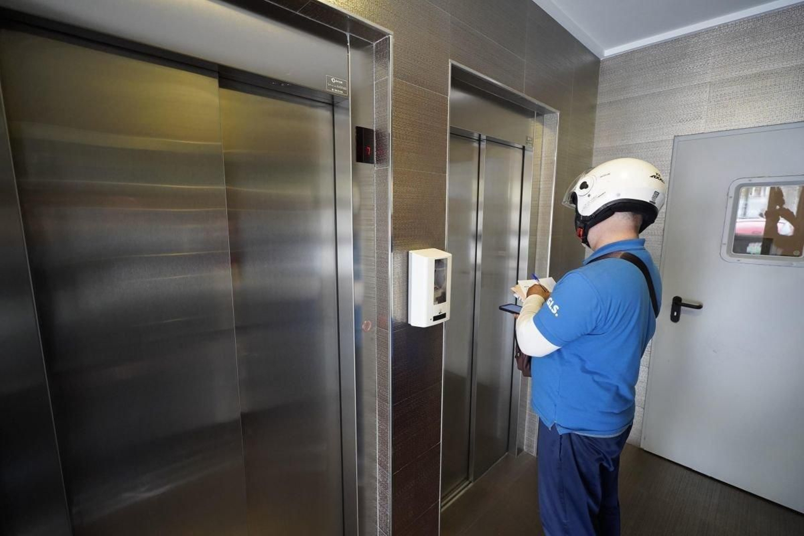 Un repartidor espera por un ascensor privado en un edificio en Vigo.