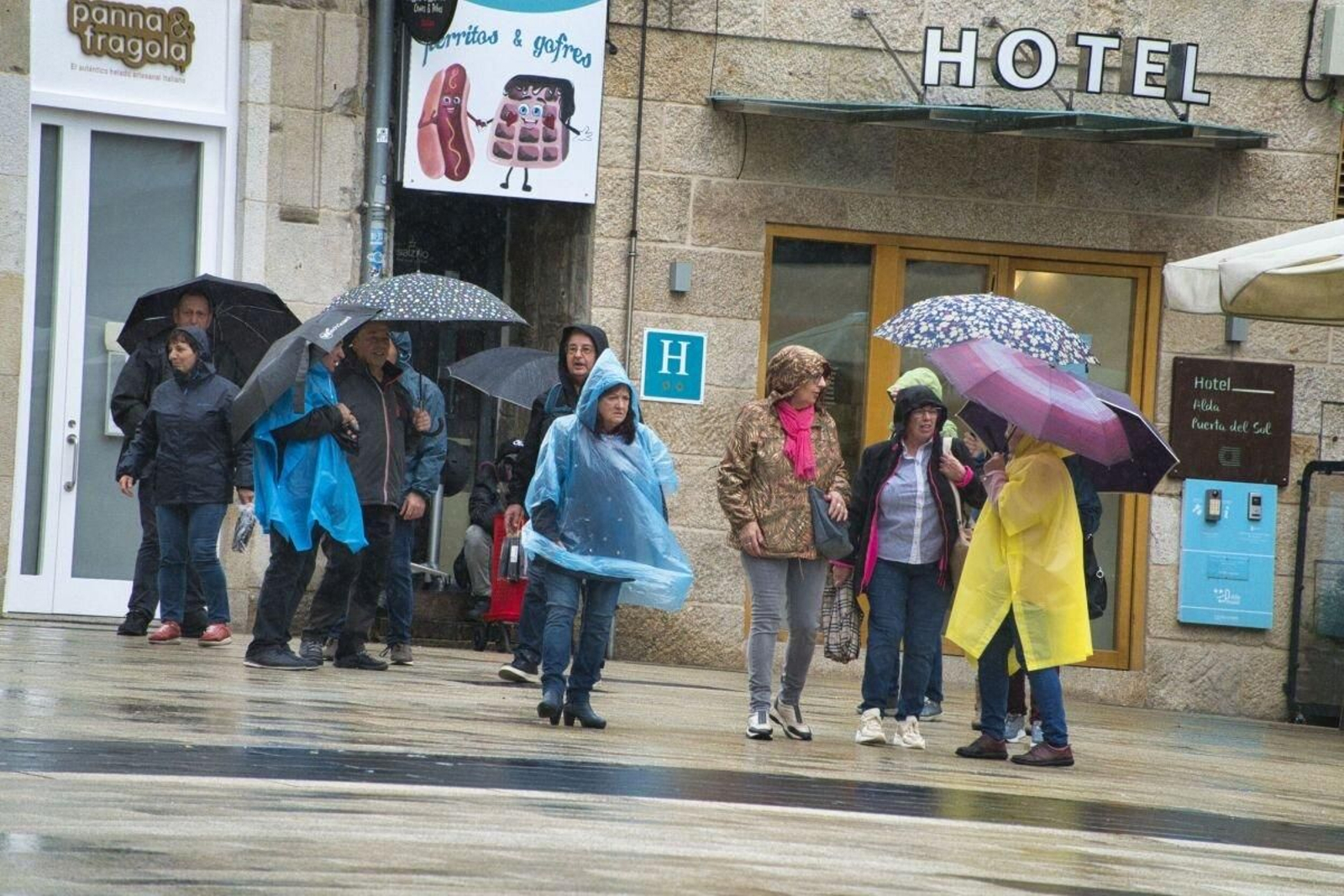 Un grupo de turistas con paraguas y chuvasqueros ayer en el centro de Vigo.