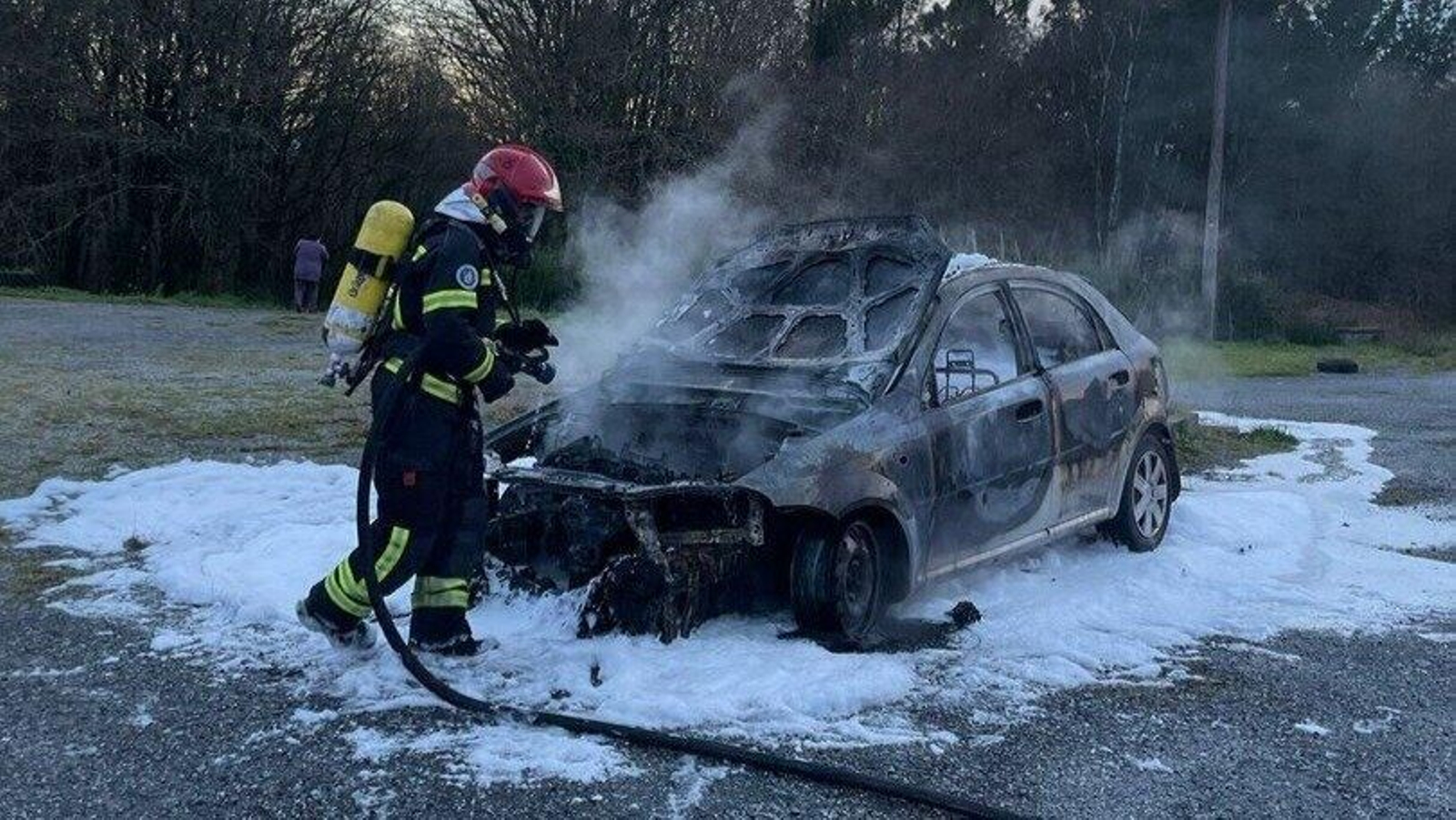 Un bombero trabaja en las labores de extinción del fuego que calcinó el coche en Vilamarín.