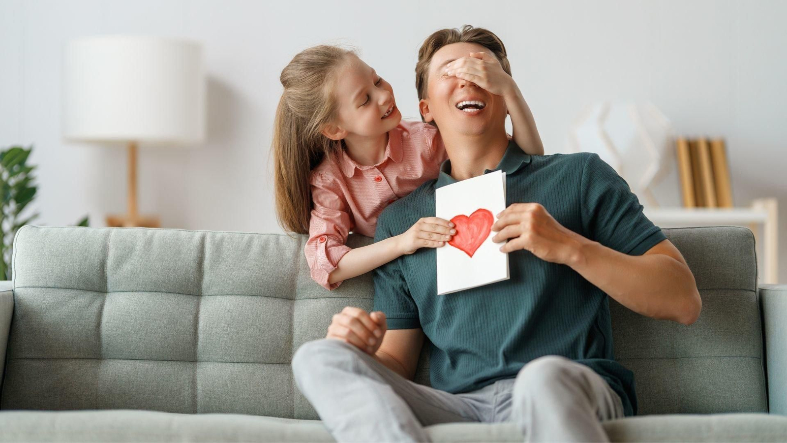 Una niña sorprende a su padre con un dibujo. // Canva