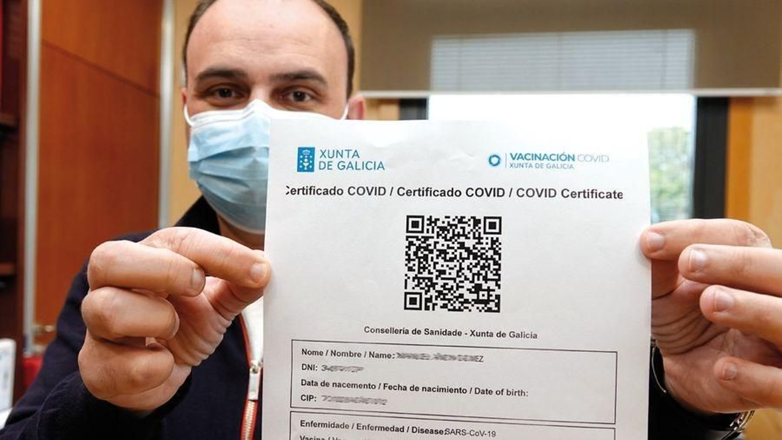 Un vacunado enseña su certificado covid.