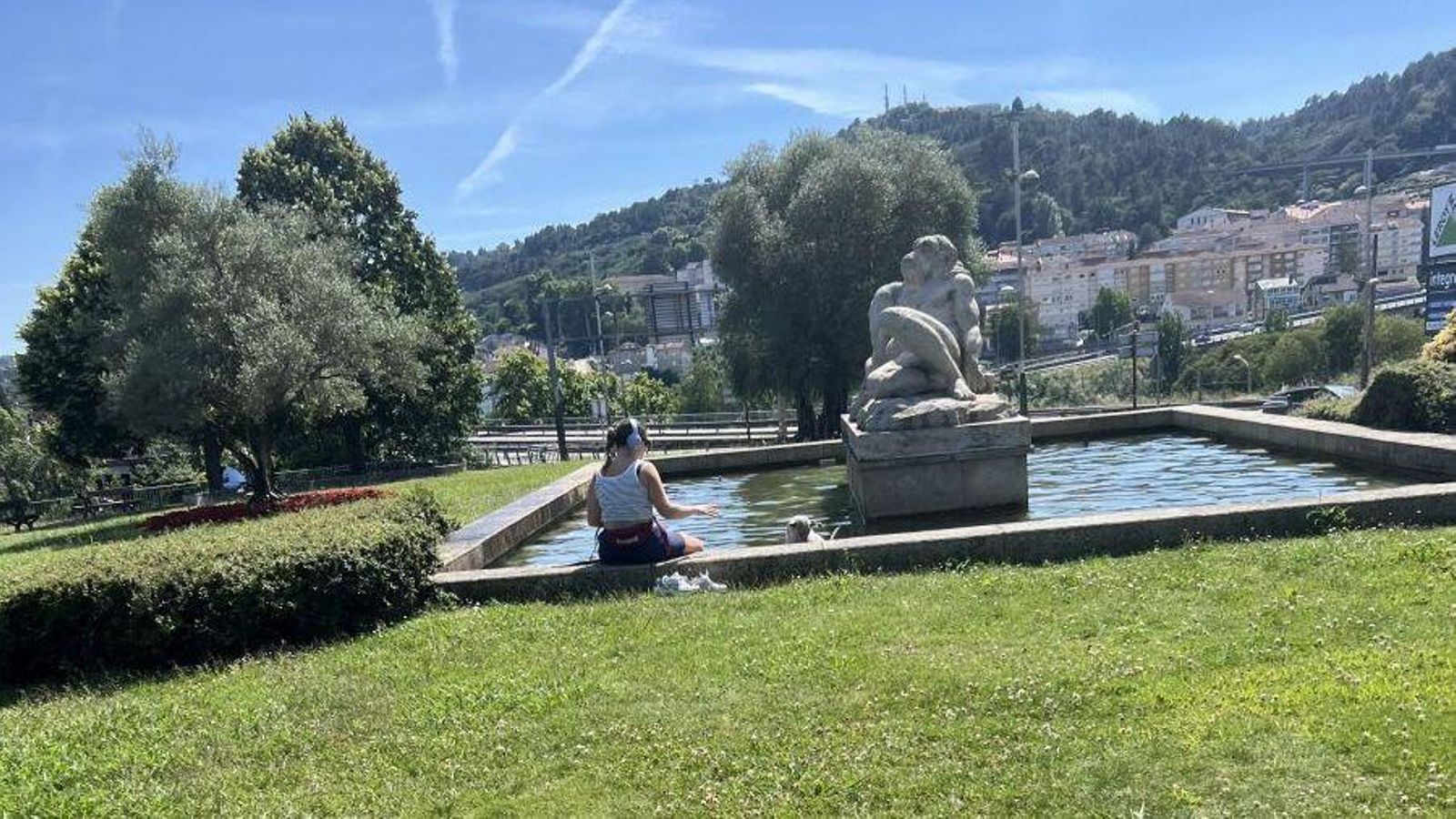 Los ciudadanos de ourense refrescándose con sus perros en una fuente al lado de la sede de la Policía Local.