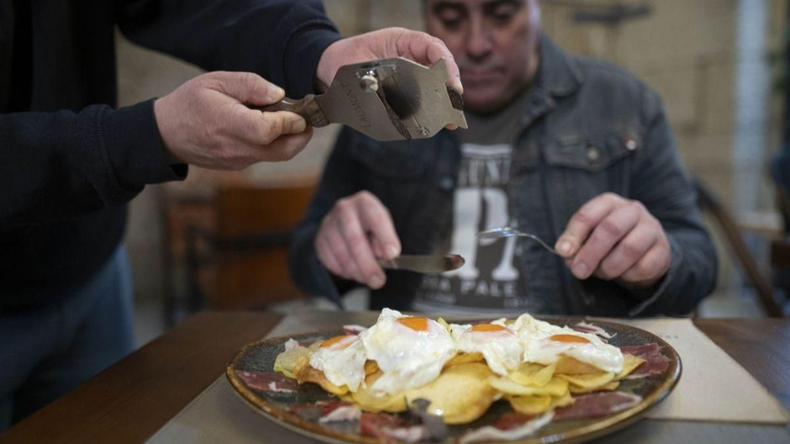 Un cliente disfrutando de huevos con trufa negra.