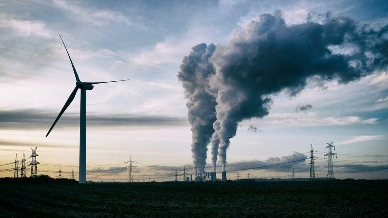 Un molino de viento, junto a una central eléctrica en España.
