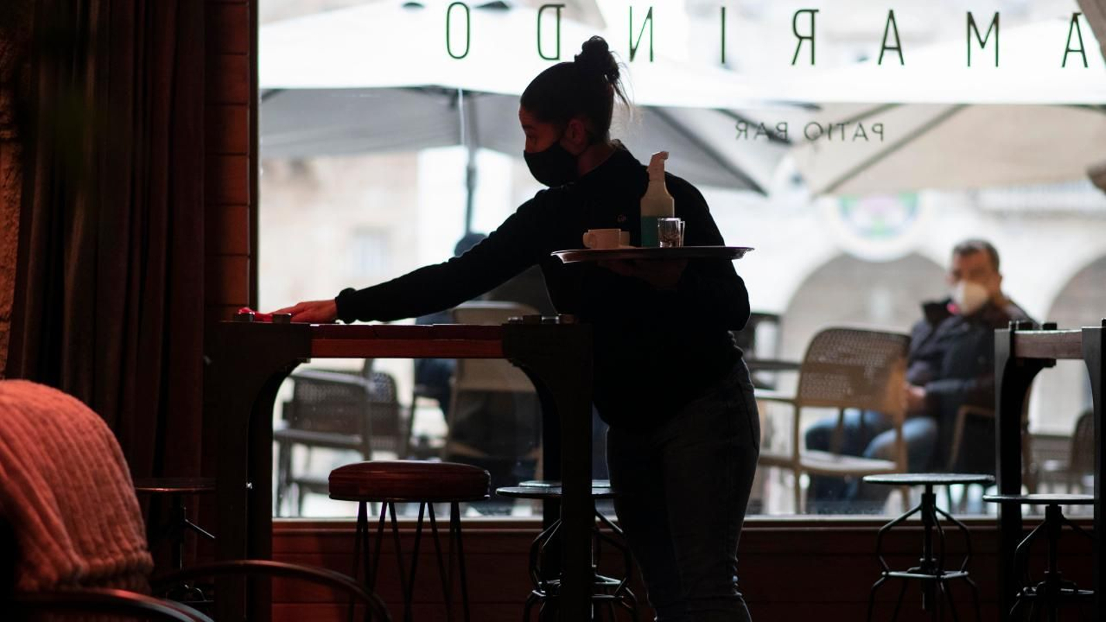 Una camarera recoge una mesa en un el interior de un bar en la Praza Maior de Ourense. XESÚS FARIÑAS