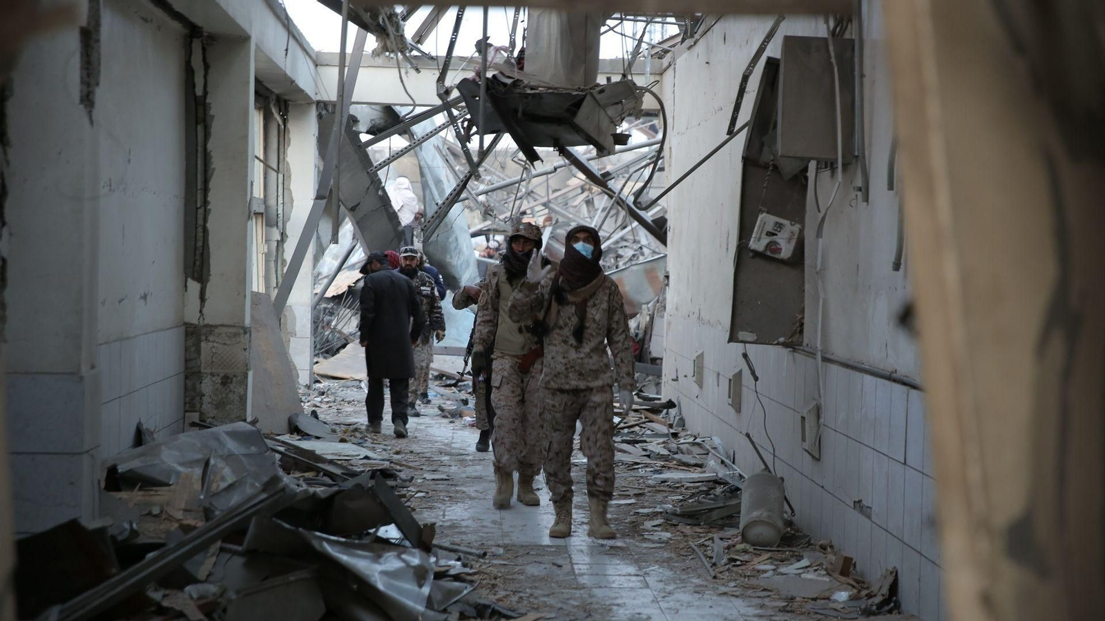 Fuerzas de seguridad talibanes recorren las ruinas devastadas de un hospital de rehabilitación de drogodependientes tras un ataque aéreo.