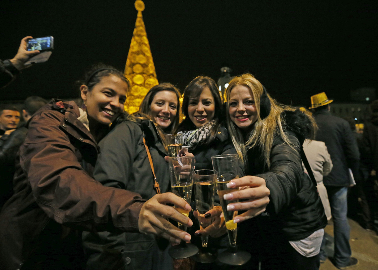 Cuatro jóvenes brindan por el año nuevo en la Puerta del Sol de Madrid.